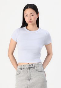 Lichtblauw cropped t-shirt met korte mouwen en een ronde hals, gemaakt van gladde stof, gecombineerd met een hooggetailleerde grijze denim rok.