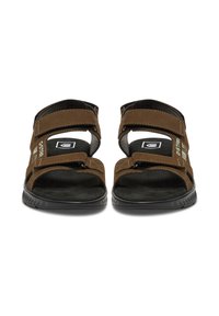 Brown suede sandals with adjustable straps, a cushioned black footbed, and a textured rubber sole. Features branding on the side.