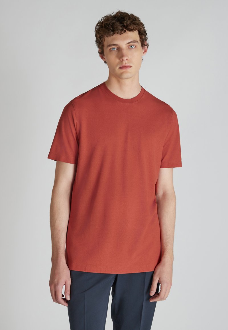 Maglietta a maniche corte, con colletto a girocollo, in cotone arancione bruciato. Design semplice con orlo dritto e senza motivi o accenti visibili.