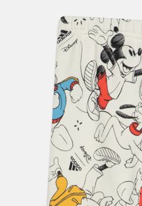 Tessuto bianco con stampe di personaggi dei cartoni animati, che presenta figure Disney. Include dettagli del logo Adidas. Materiale morbido e leggero.