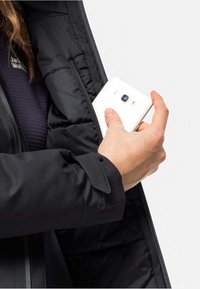 Schwarze Pufferjacke mit einem Reißverschluss, in der eine Hand ein weißes Smartphone aus der Innentasche greift.