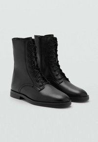 Botines de cuero negro hasta el tobillo con cordones en la parte delantera y cremallera lateral. Presentan un acabado suave, punta redonda y tacón bajo apilado.