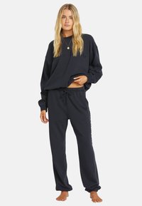 Marineblå sweatshirt og matchende sweatpants lavet af blødt stof. Sweatshirten har en afslappet pasform med sænkede skuldre; bukserne har en justerbar drawstring i taljen.