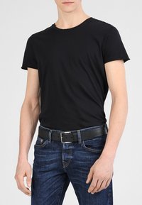 T-shirt nera in cotone con collo a giro, abbinata a jeans denim blu scuro e una cintura in pelle nera con fibbia argentata.