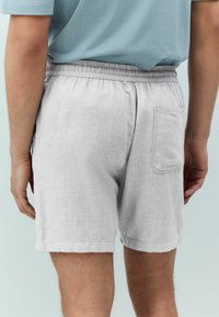 Light gray shorts made of a textured fabric, featuring an elastic waistband and a back pocket, with rolled hems for a casual look.