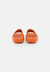 Orange gummisandaler med öppet bakparti, texturerad sula och släta kanter. Lätta, minimalistiska i design.
