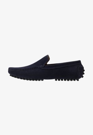 Marineblauwe suede instap loafers met een ronde neus en een getextureerde rubberen buitenzool, voorzien van opvallende stiksels langs de bovenrand.