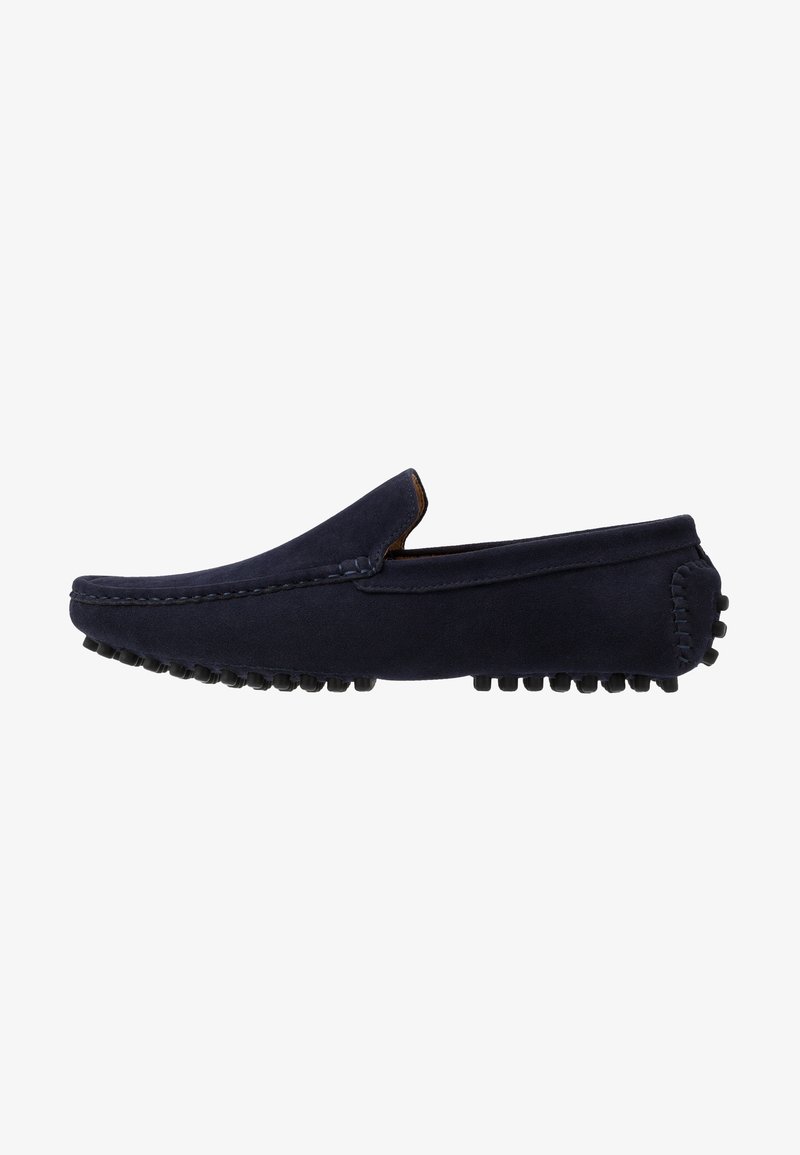Navy blue suede slip-on loafers with a rounded toe and textured rubber outsole, featuring prominent stitching along the upper edge.