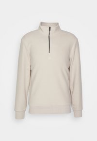 Pullover in pile color crema con mezza zip nera, colletto alto, polsini e orlo a costine, e piccolo logo bianco ricamato sul petto.