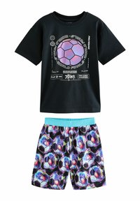 T-shirt noir à manches courtes avec un design de ballon de football graphique et un texte blanc, associé à un short coloré avec un motif de ballon de football.