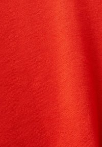 Gros plan d'un tissu tricoté rouge vif montrant des mailles fines, régulières et une texture douce.