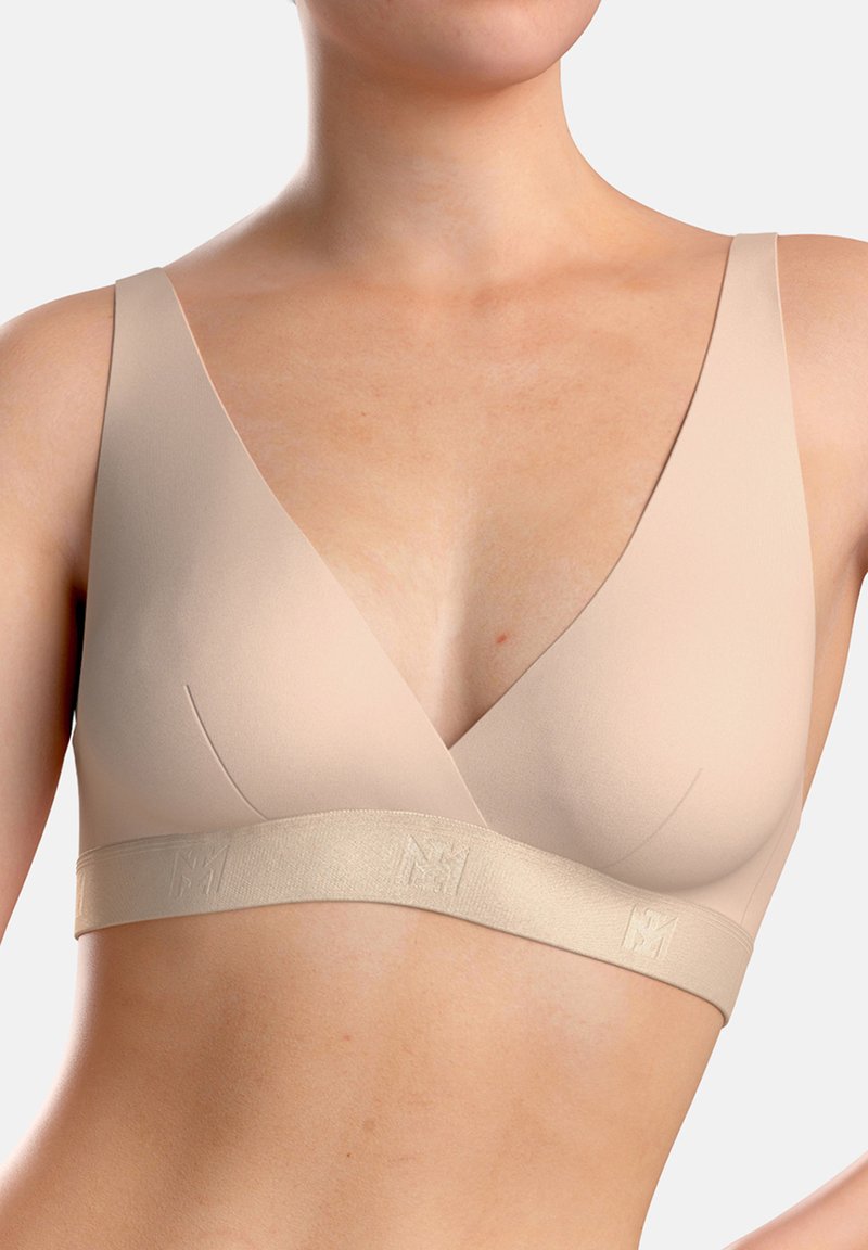 Nude-colored wireless bra with triangular cups, soft fabric, and a wide band featuring a subtle logo. Simple design and smooth texture.