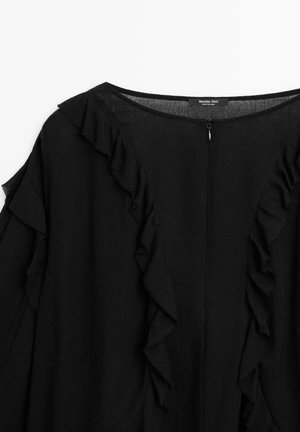 Blusa nera con dettagli arricciati lungo il collo e le maniche, con chiusura a zip sul retro. Realizzata in tessuto leggero.