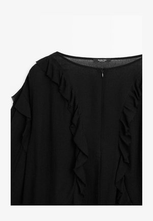 Blouse noire avec des accents froncés le long de l'encolure et des manches, dotée d'une fermeture éclair à l'arrière. Fabriquée en tissu léger.