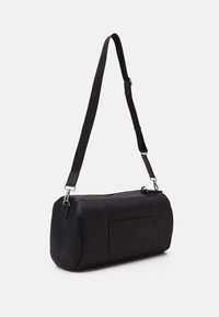 Svart läderaxelväska med strukturerad yta, rundad form, justerbar rem och dragkedjestängning. Har en ytterficka.