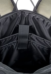 Black backpack interior featuring three compartments, textured lining, and a central strap for organization. Smooth fabric with structured design.