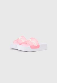 Sandales à glissière transparentes roses avec des semelles blanches, présentant un logo blanc sur la sangle. Texture lisse et design arrondi.