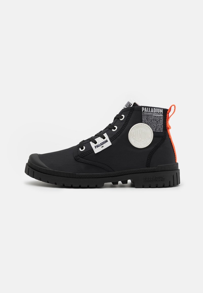 Botte montante noire Palladium avec patchs logo blancs, lacets noirs, semelle robuste et languette orange au talon.