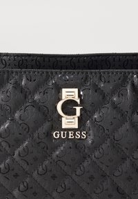 Borsa a tracolla nera in sintetico trapuntato con logo "G" in tonalità oro, finitura lucida e sottile texture a motivo su tutta la superficie.