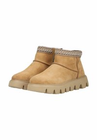 Bottines en suède beige clair avec une tige texturée, présentant des coutures décoratives au niveau de la cheville et une semelle en caoutchouc beige épaisse.