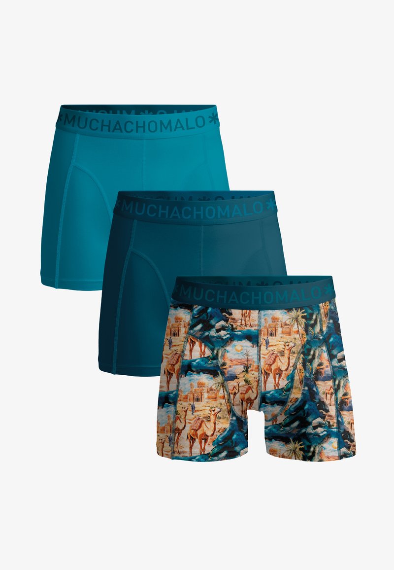 Trois boxers pour hommes en nuances de bleu ; deux unis et un avec un motif chameau et désert, tous avec des ceintures "MUCHACHOMALO".