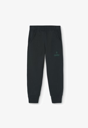 Black sweatpants with elastic waistband, side pockets, and ribbed cuffs. Features a small green logo on the thigh. Soft fabric texture.