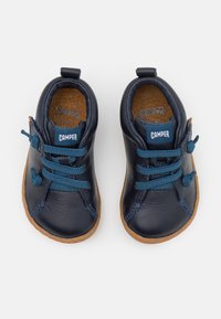 Chaussures en cuir marine pour tout-petits avec semelles en caoutchouc, bouts ronds, lacets bleus et accents beige. Étiquette de logo sur la languette. Doublure intérieure texturée.