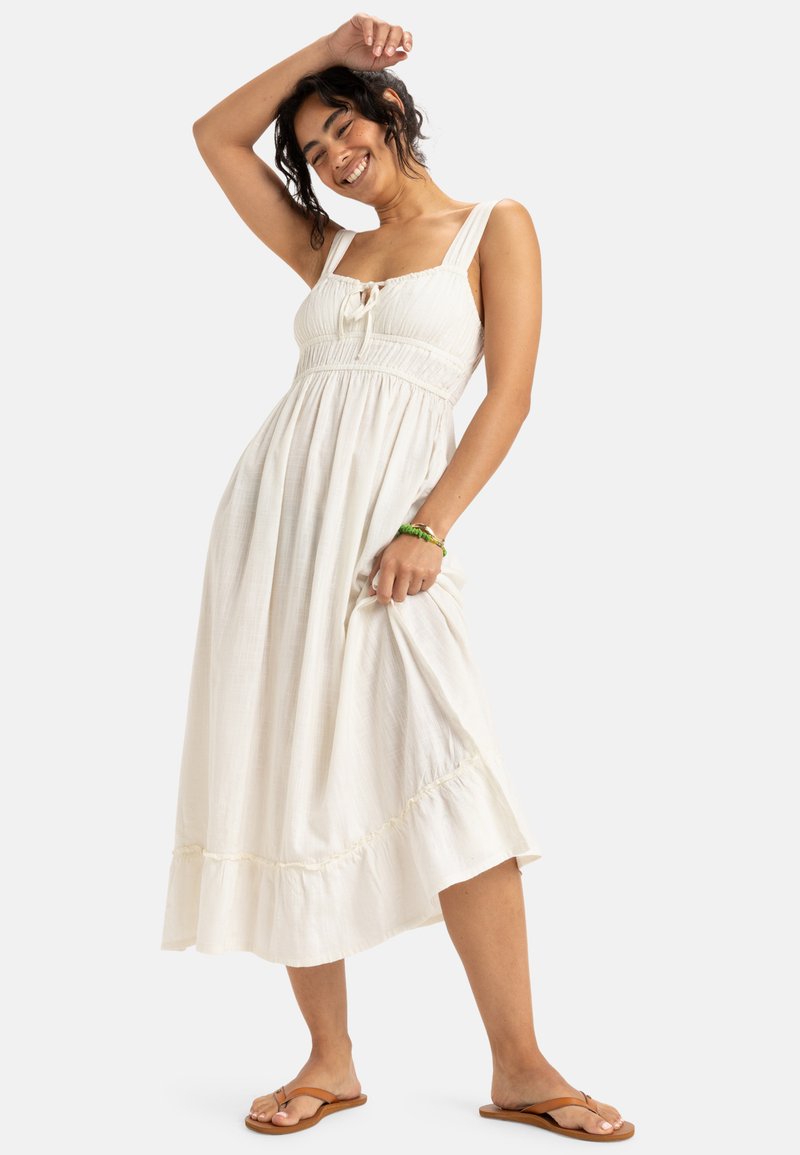 Sukienka maxi w off-white tkaninie z marszczoną górą, szerokimi ramiączkami i falbaniastym dołem. Posiada detal w postaci związania z przodu oraz luźny krój.