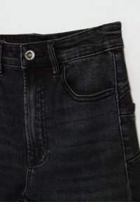 Černé džínové kalhoty s klasickým pětivreckovým designem, s kovovým zapínáním, jemnou texturou a úzkým střihem.