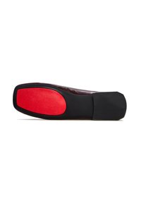 Semelle noire avec une section rouge vif au talon, texture lisse, finition semi-brillante, forme légèrement arrondie, matériau en caoutchouc.
