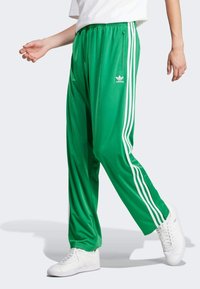 Green polyester tracksuit pants featuring white side stripes, elastic waistband, and a small white logo on the front.