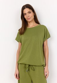 Green short-sleeve T-shirt made of soft fabric, featuring a relaxed fit, round neckline, and rolled cuff details. Worn with matching pants.