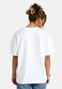 T-shirt bianco in cotone con vestibilità rilassata, caratterizzato da un collo a giro e maniche corte. Texture liscia senza motivi o grafiche visibili.
