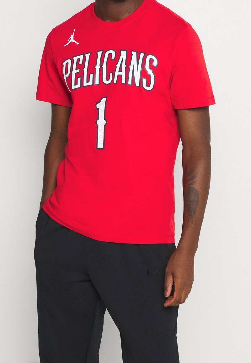 Red cotton t-shirt with "PELICANS" and number "1" printed in white and gray. Features a Jumpman logo on the upper left. Crew neckline, short sleeves.