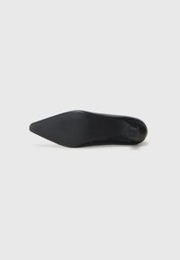 Zapatos de tacón negro con punta afilada, acabado liso, tacón ligeramente elevado y suela texturizada para un mejor agarre. Diseño minimalista y silueta elegante.