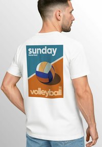 Weißes T-Shirt mit einem Grafikdesign auf der Rückseite, das einen bunten Volleyball, die Texte "Sonntag" und "Volleyball 75" vor einem blau-orangefarbenen geometrischen Hintergrund zeigt.
