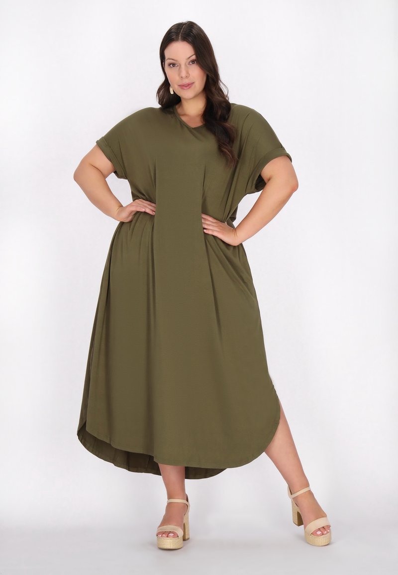 Rochie maxi verde măsliniu, cu mâneci scurte, croi lejer, margine rotunjită și două buzunare laterale; asortată cu sandale cu platformă bej.