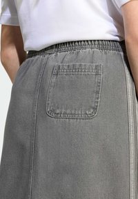 Grå denimskjørt med elastisk midje, med en enkelt baklomme og subtile sømdetaljer langs siden.