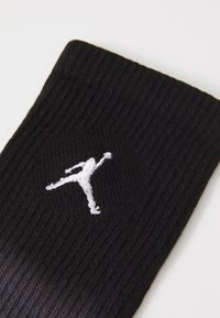 Calza nera in maglia con texture a coste e logo Jumpman ricamato in bianco. Il design enfatizza la durata e il comfort.