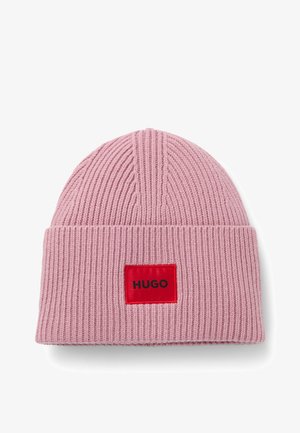 Berretto lavorato a maglia rosa con texture a coste e risvolto. Una patch rettangolare rossa sul davanti mostra la parola "HUGO" in nero.