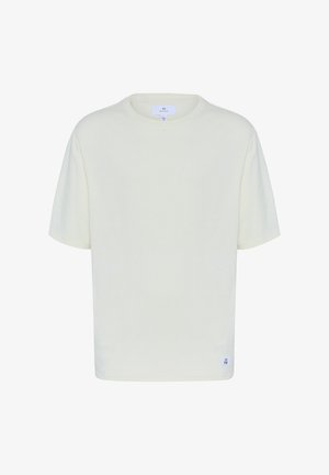 Krém színű póló, kerek nyakkivágással, rövid ujjakkal és laza fazonnal. Az alsó baloldalon egy kis logócímke található.