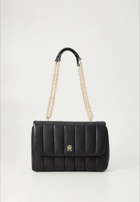 Czarna pikowana skórzana torebka na złotym łańcuszku z czarnymi skórzanymi akcentami; z przodu znajduje się złote logo.