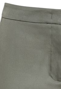 Tessuto verde oliva chiaro con una finitura morbida e testurizzata. Presenta una cintura piatta e cuciture minime, con una tasca laterale visibile.