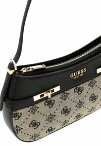 Sac à main en cuir synthétique noir avec un panneau beige texturé présentant un motif de logo répété, des ferrures dorées et une fermeture éclair.