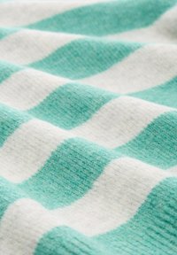 Gestreifter Stoff in abwechselnden Aqua- und Weißtönen, mit einer weichen, strukturierten Oberfläche und einem wellenförmigen Muster, das über die Fläche verläuft.