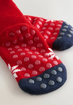 Piros zoknik textúrált, csúszásgátló talppal. Tengerészkék lábujj és sarok díszítéssel, bordázott mintával. Puha, plüss anyag.