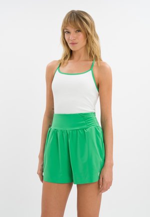 Sportoutfit für Frauen, bestehend aus einem weißen Tanktop mit grünen Akzenten und grünen Shorts mit einem gerafften Bund. Aus glattem, atmungsaktivem Material.
