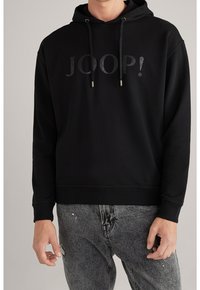 Sudadera negra con capucha que cuenta con un logo texturizado "JOOP!" en la parte frontal, con cordones y puños y dobladillo acanalados. Combinada con jeans grises.