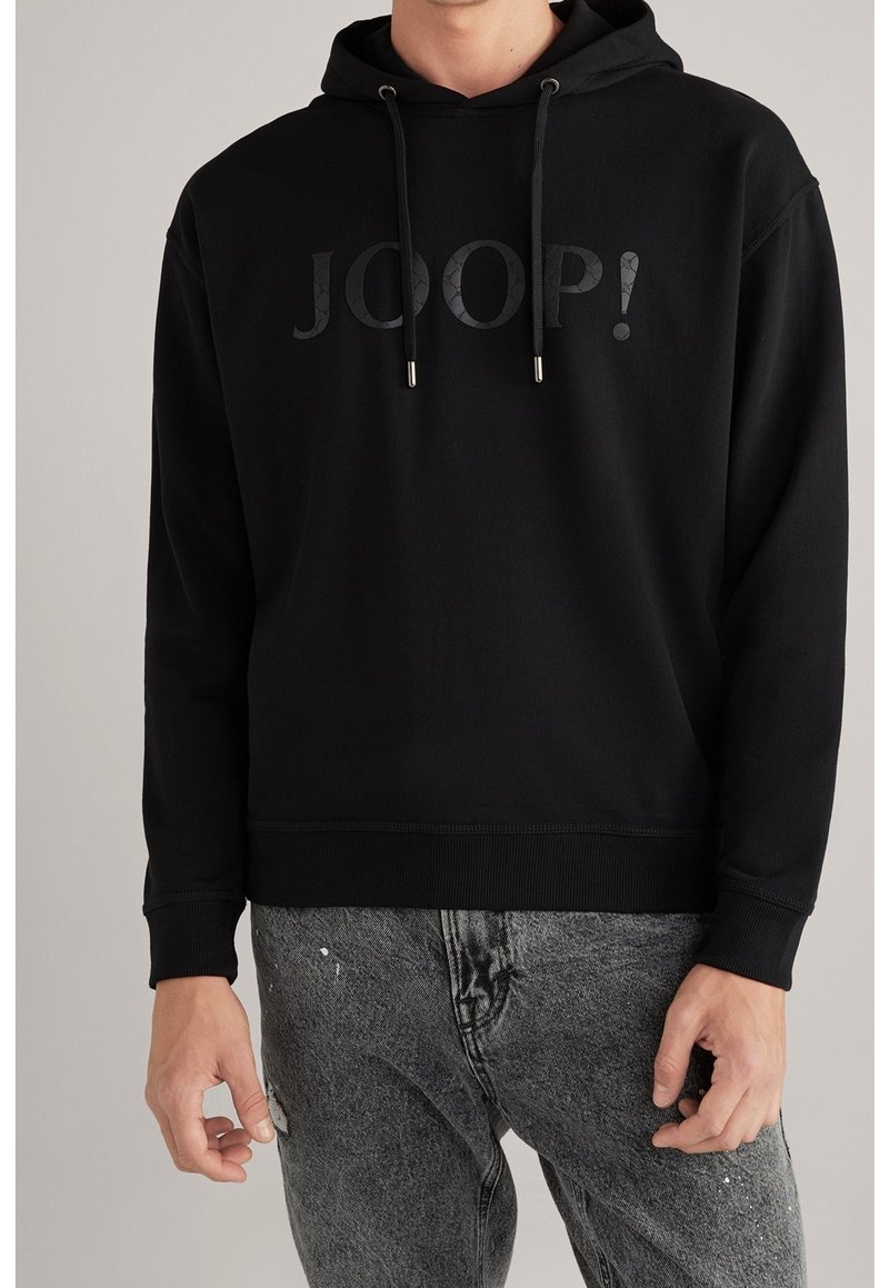 Sudadera negra con capucha que cuenta con un logo texturizado "JOOP!" en la parte frontal, con cordones y puños y dobladillo acanalados. Combinada con jeans grises.