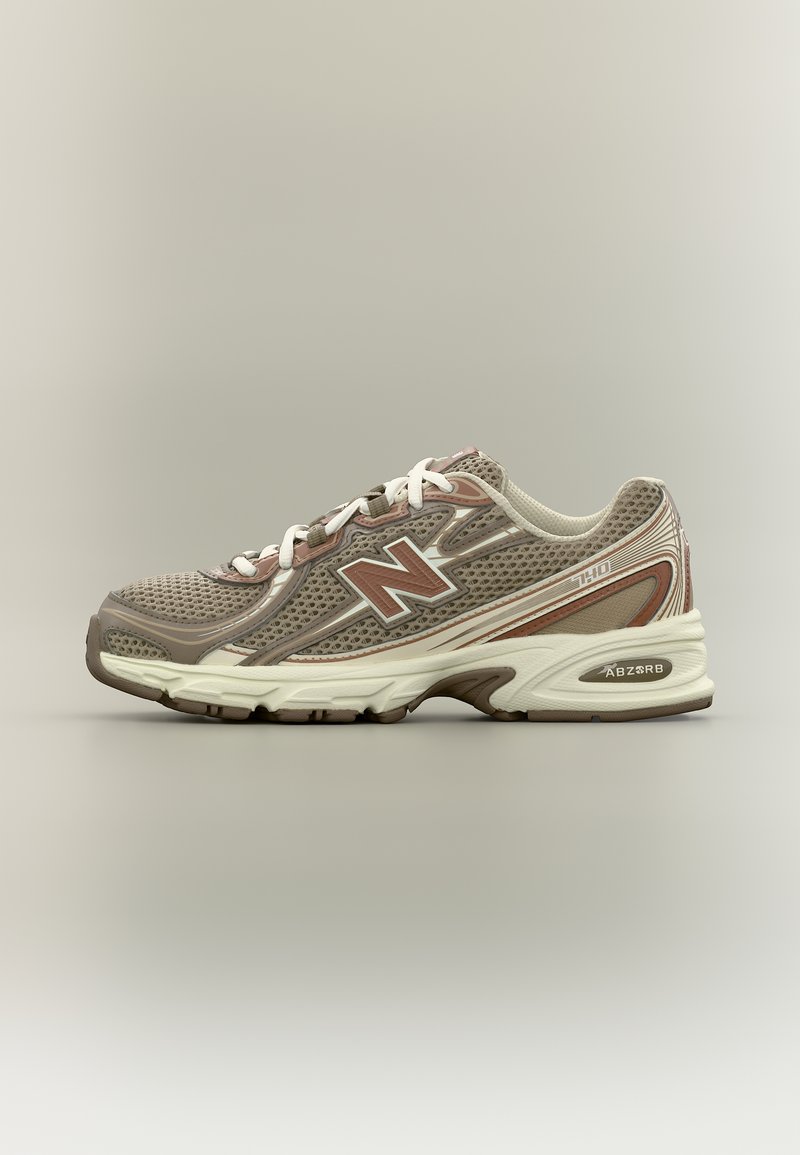 Μπεζ και καφέ παπούτσι για τρέξιμο New Balance 740 με επάνω μέρος από δίχτυ, λευκά κορδόνια και μαλακή σόλα σε ουδέτερο γκρι φόντο.